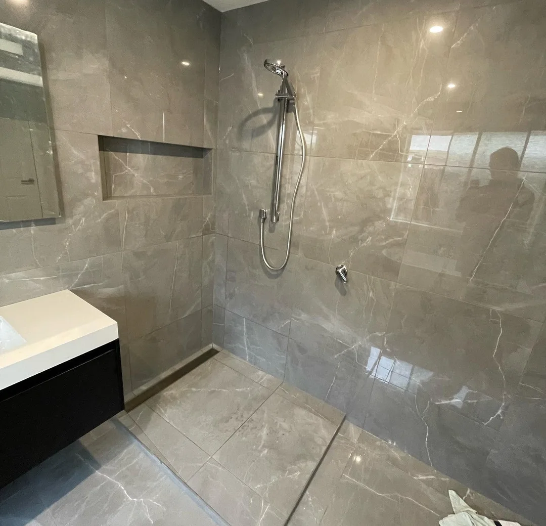 Shower area with large-format stone-look tiles in a finished bathroom