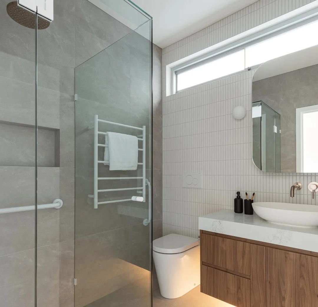Finished bathroom with shower screen, timber vanity and heated towel rail