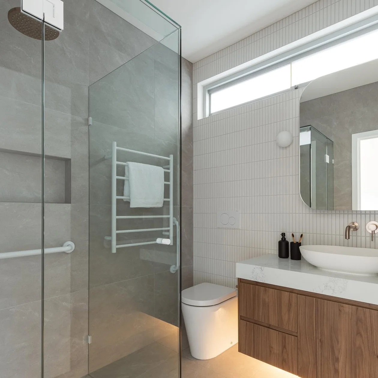 Completed bathroom with a shower screen, timber vanity and heated towel rail