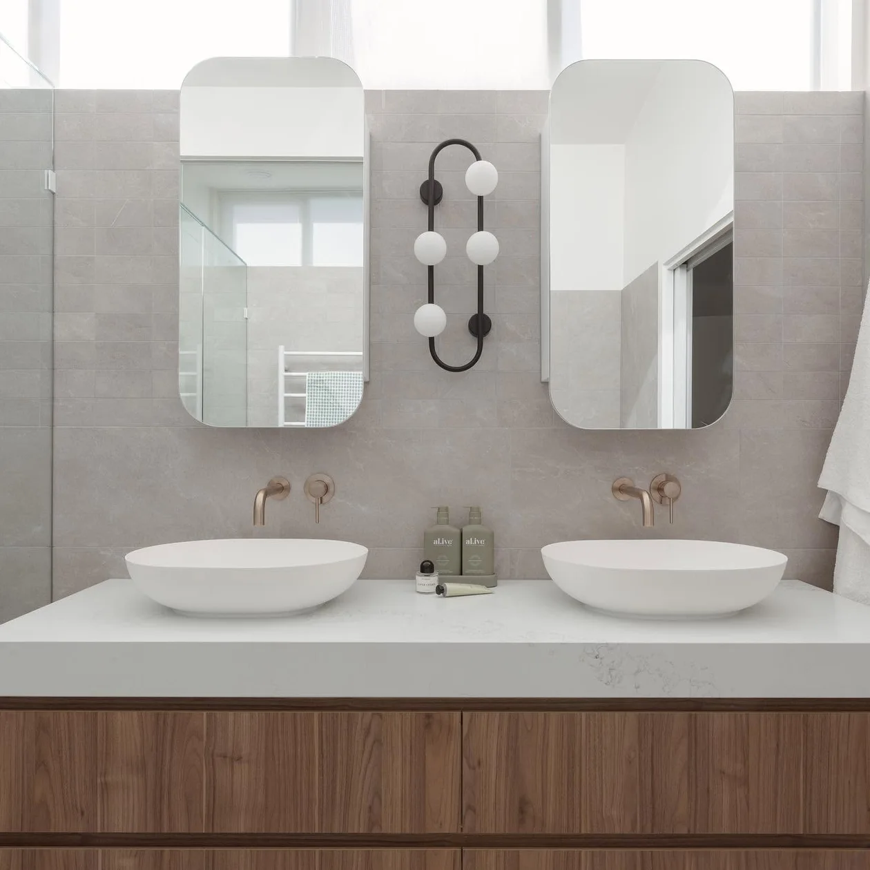 Twin basin vanity with brass tapware in a completed bathroom