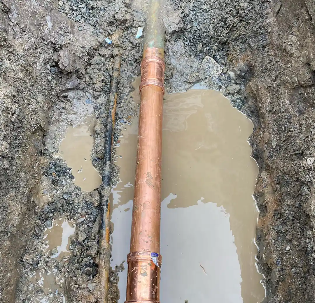Copper water service pipe exposed in a wet trench during a renewal