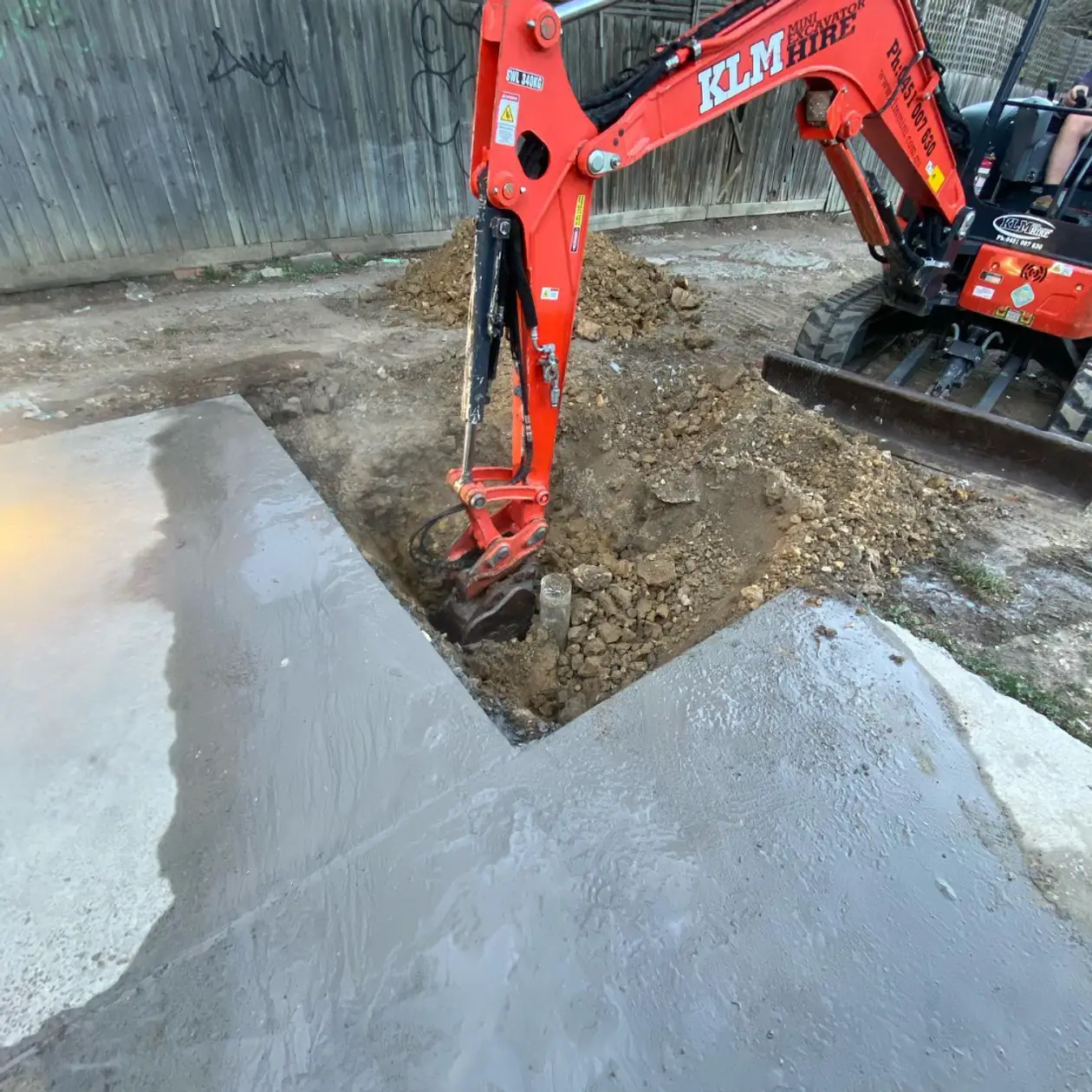 Excavator digging a targeted excavation over a located drain