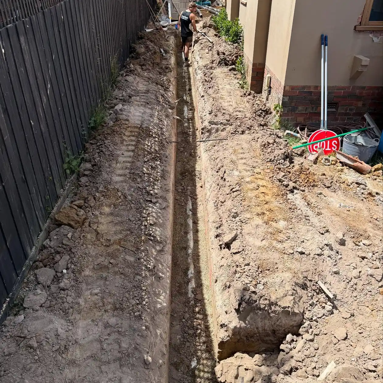 Drainage trench excavated along the side of a house between the fence and the wall