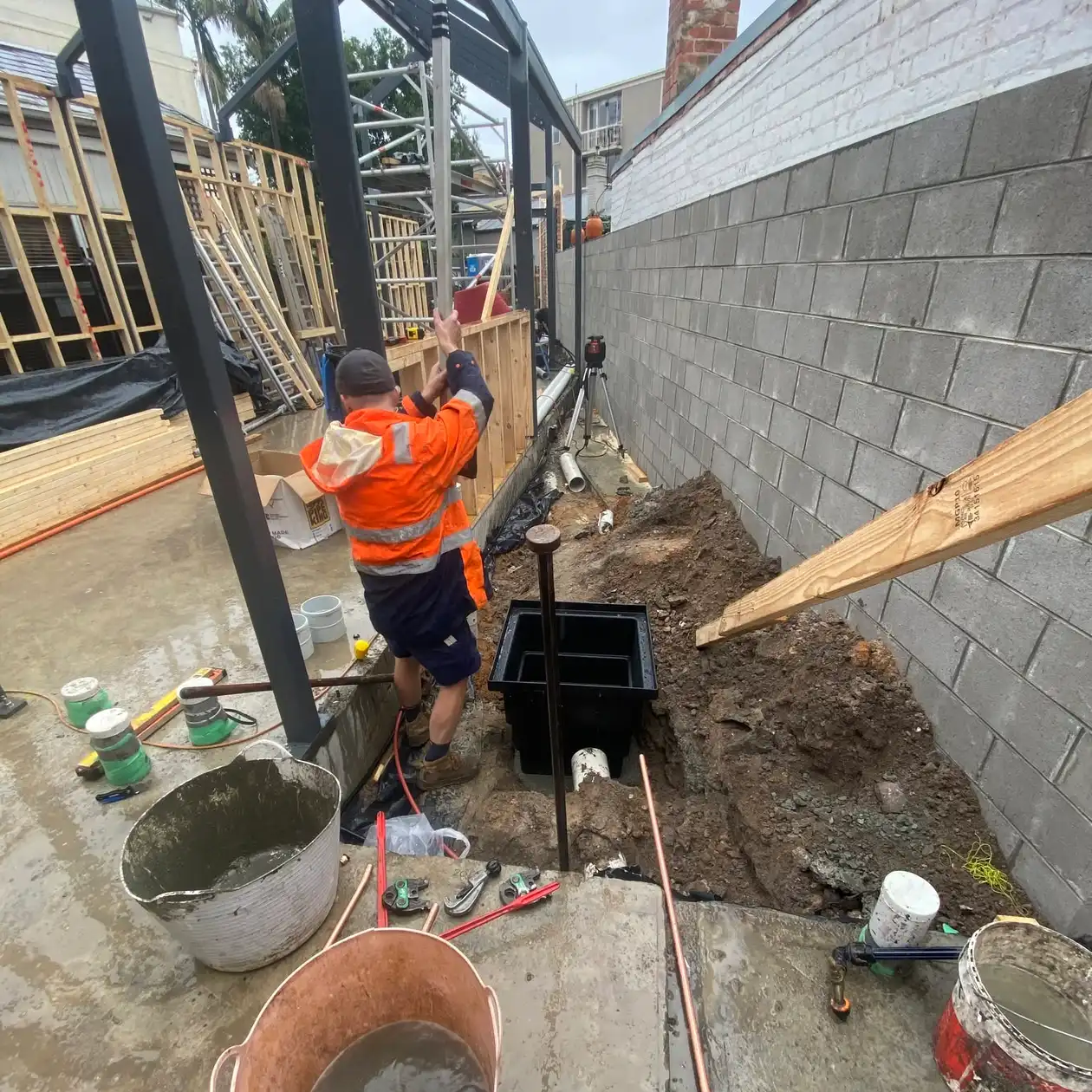 Plumber in high visibility gear working on pipework at a residential site